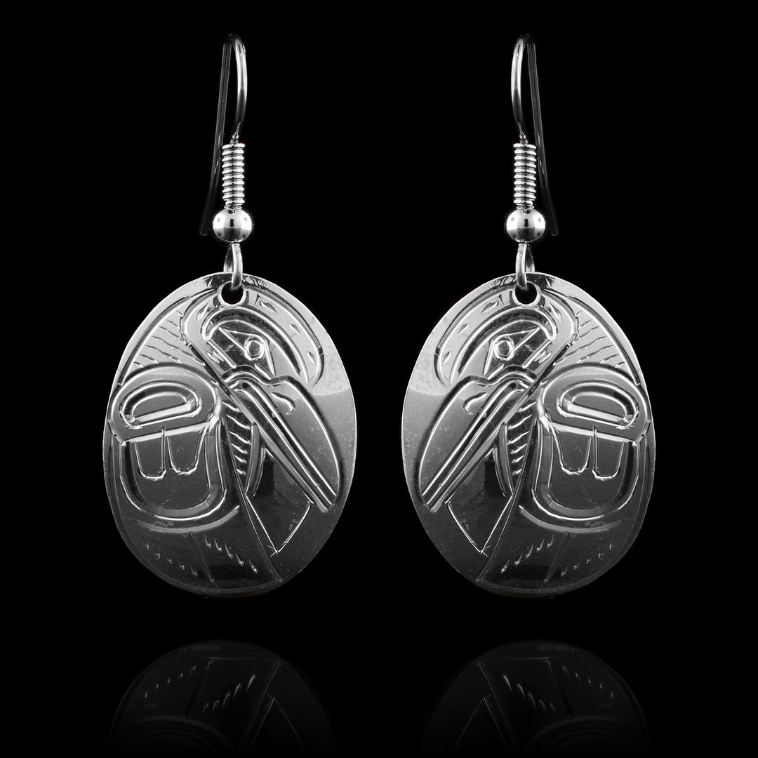These Hummingbird earrings have oval shaped hangs made from sterling silver. There is a side profile depiction of the Hummingbird carved into the hangs. Its head is facing down and one if its wings runs down the side of the piece.
