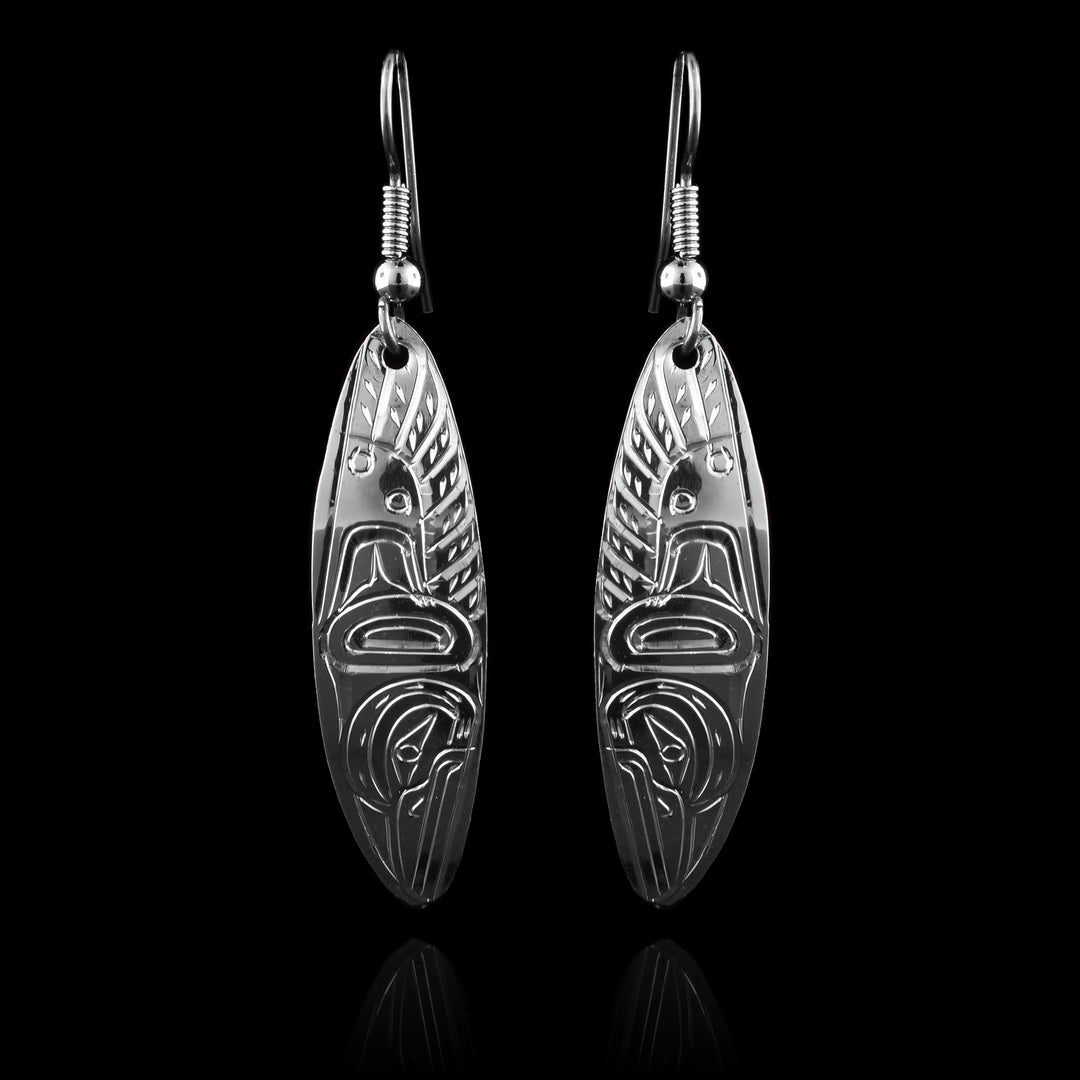 These Hummingbird drop earrings has long, oval shaped hangs made from sterling silver. There is a unique depiction of the Hummingbird carved into the hangs at a side profile. There is one wing with feather details at the top half of the hangs and its head is facing down at the bottom of the hangs.