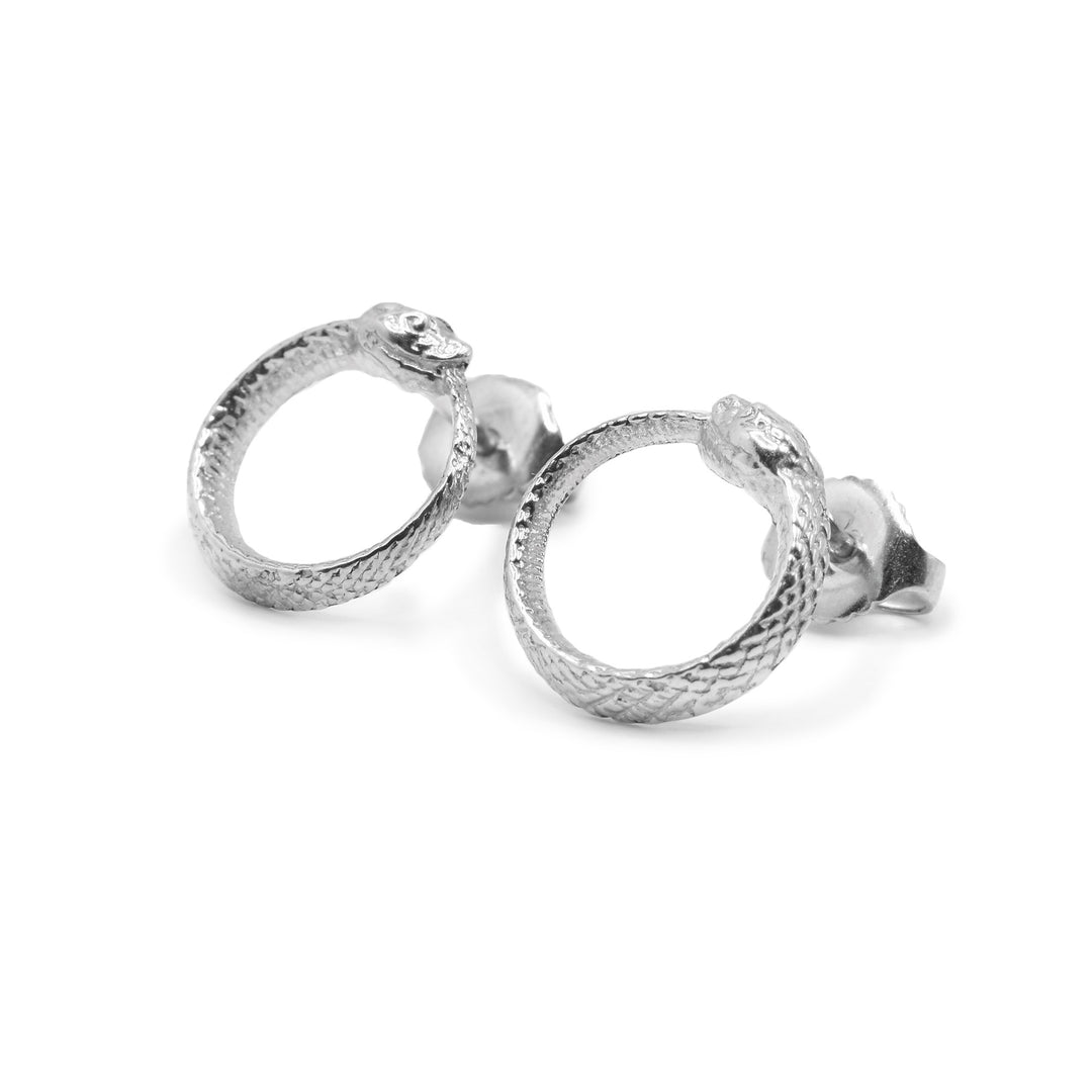 These ouroboros earrings are made from sterling silver and are circle shaped. The studs are attached to the tops of the circles and they look like snakes with their tails curled up into their mouths. There are scale details on the studs and they have detail heads.