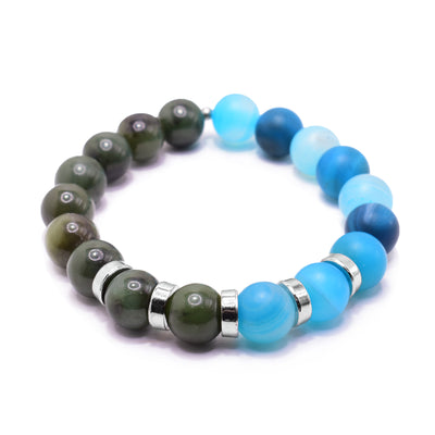 This blue agate bracelet has small, sphere shaped beads made from BC jade and dyed blue agate. Half the piece is jade and the other is agate. There are five rhodium plated spacers between the beads in the center of the piece. The spacers are round and flat.