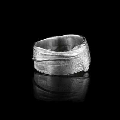 This chunky silver ring is made from sterling silver and has flowing designs on the surface of it. The piece is made by casting metal into wax so it mimics the appearance of it wax mold. The ring is chunky and has a large gauge.