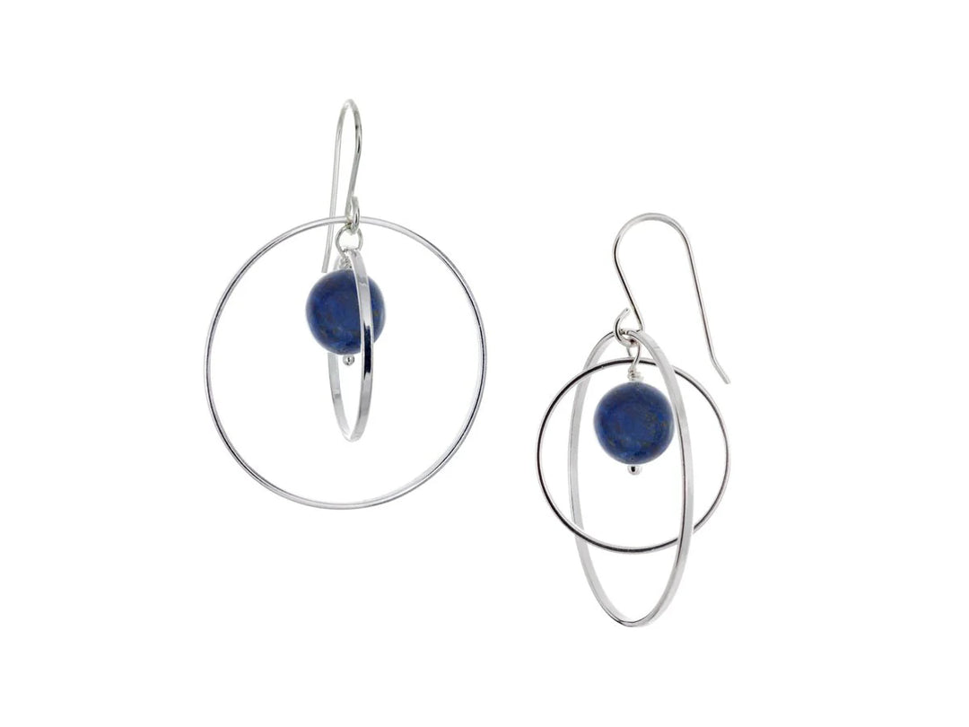 These hoop dangle earrings have large, sterling silver hoops with a smaller one inside of it. In the middle is a sphere shaped lapis lazuli bead. All of these pieces are dangling and fit inside each other. The hoops are free to orbit around the gem.