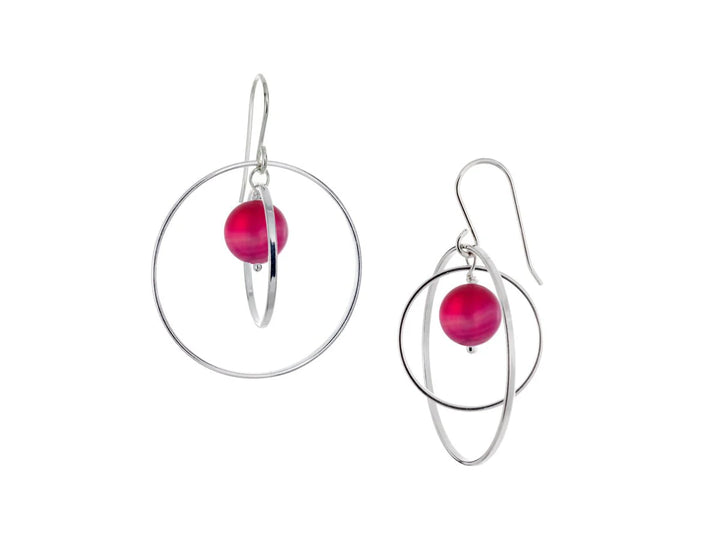 These hoop dangle earrings have large, sterling silver hoops with a smaller one inside of it. In the middle is a sphere shaped pink agate bead. All of these pieces are dangling and fit inside each other. The hoops are free to orbit around the gem.