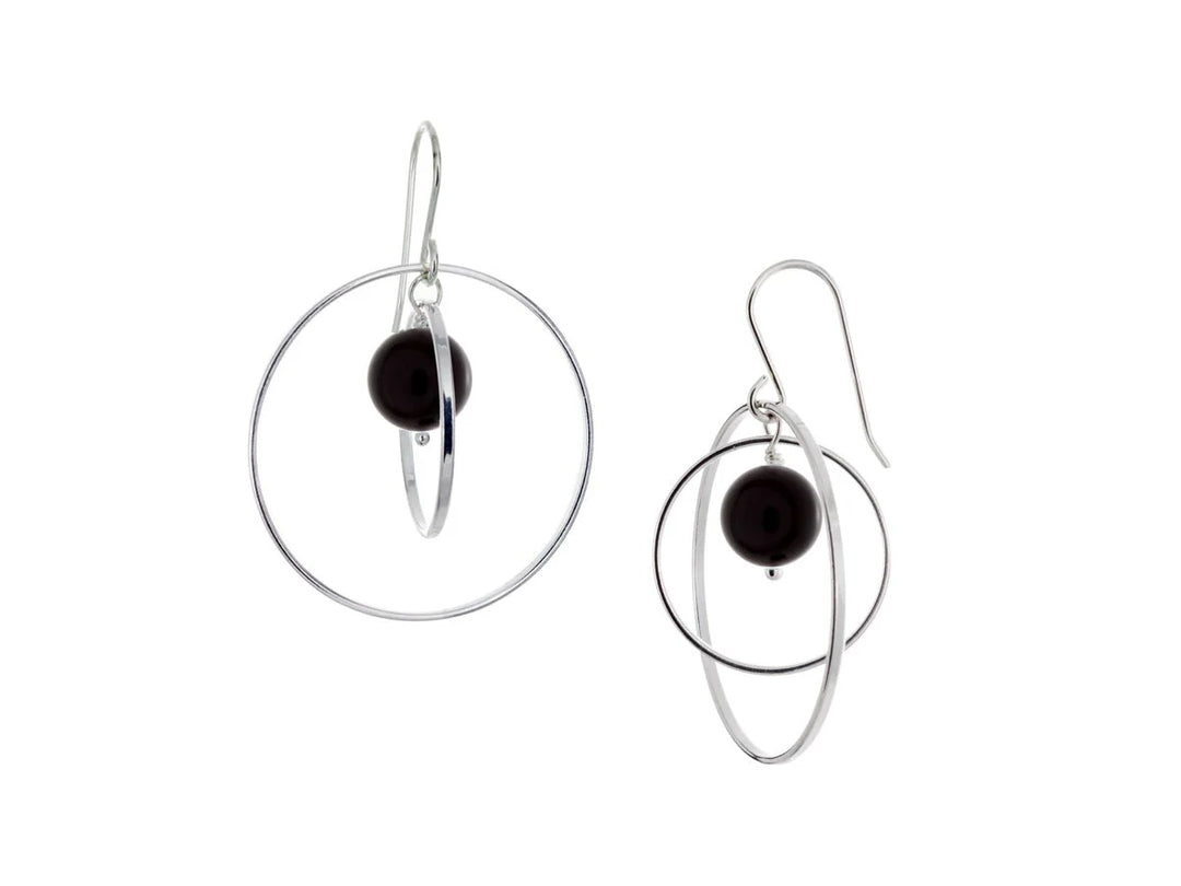 These hoop dangle earrings have large, sterling silver hoops with a smaller one inside of it. In the middle is a sphere shaped black onyx bead. All of these pieces are dangling and fit inside each other. The hoops are free to orbit around the gem.