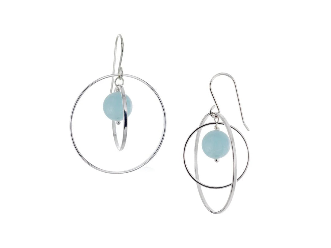 These hoop dangle earrings have large, sterling silver hoops with a smaller one inside of it. In the middle is a sphere shaped aquamarine bead. All of these pieces are dangling and fit inside each other. The hoops are free to orbit around the gem.