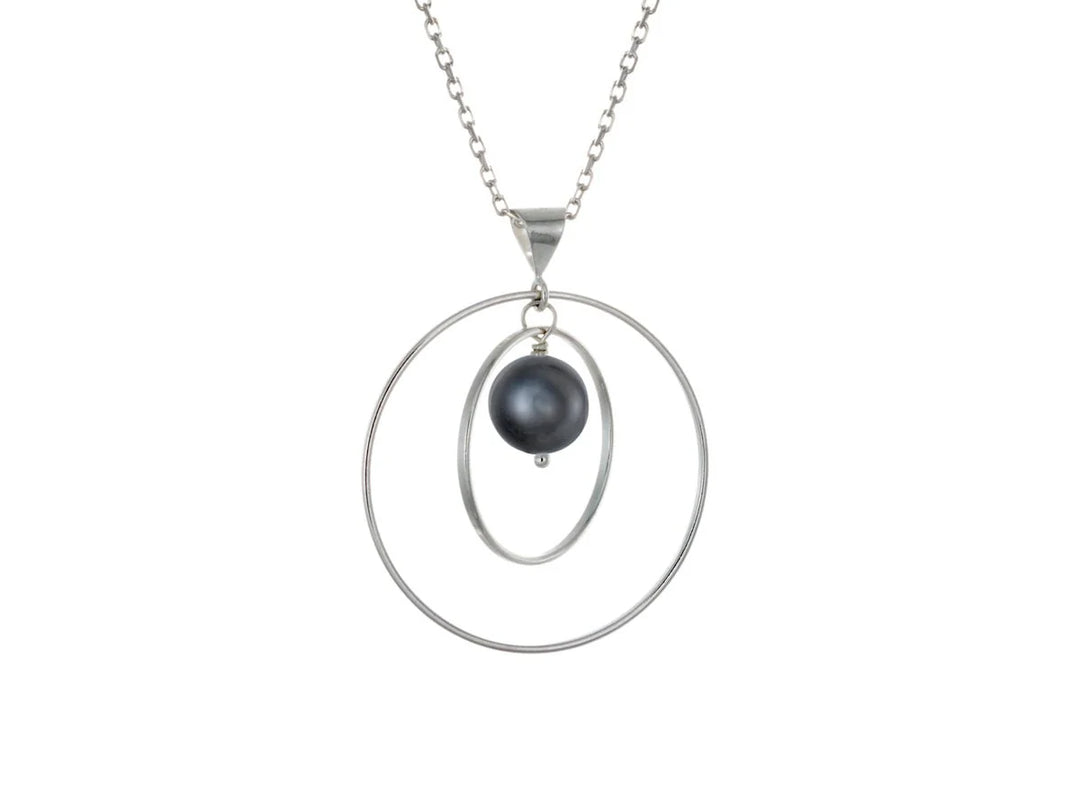 This black pearl necklace has a large sterling silver hoop with a smaller hoop in the middle of it and a sphere shaped black pearl bead in the center of them. All of these pieces are suspended and can orbit around each other.
