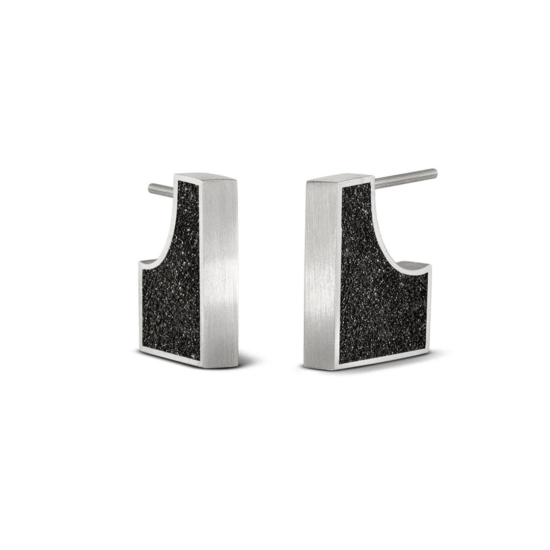 These stainless steel stud earrings are rectangular in shape with a circular portion cut out at the post to fit the earlobe. Both sides have a black concrete with diamond dust finish. The rest of each stud is stainless steel.