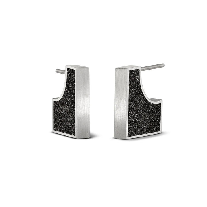 These stainless steel stud earrings are rectangular in shape with a circular portion cut out at the post to fit the earlobe. Both sides have a black concrete with diamond dust finish. The rest of each stud is stainless steel.