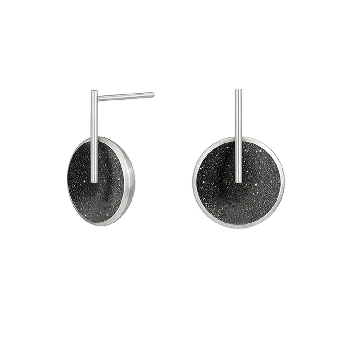 These stainless steel earrings feature a round, domed centerpiece with black-tinted concrete and diamond dust. A thin stainless steel rod has been attached to the front and extends above to the post.