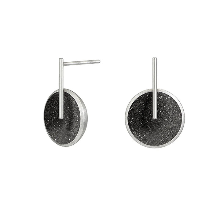 These stainless steel earrings feature a round, domed centerpiece with black-tinted concrete and diamond dust. A thin stainless steel rod has been attached to the front and extends above to the post.