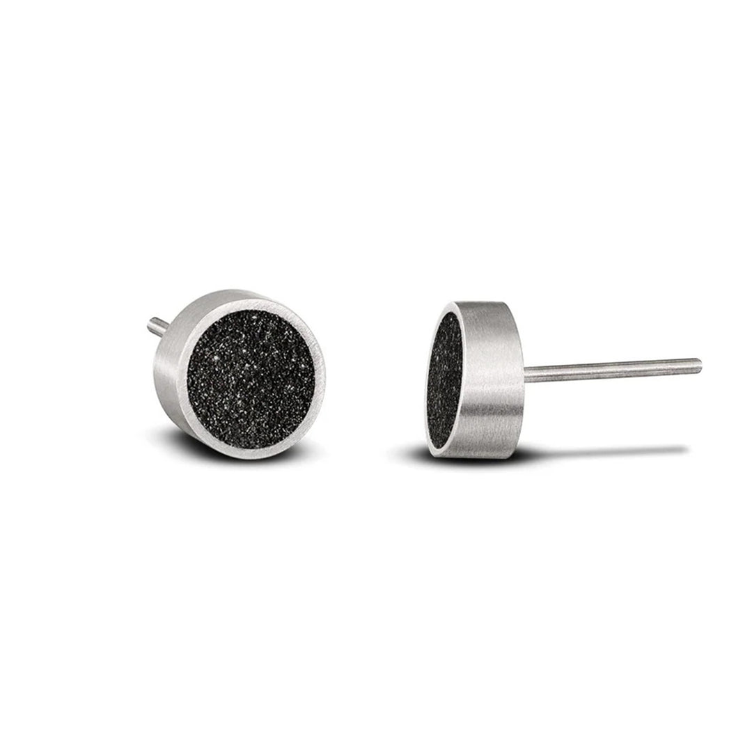 These delicate stainless steel stud earrings feature a dark, shiny centerpiece made of concrete and diamond dust. The border encasing it is stainless steel.