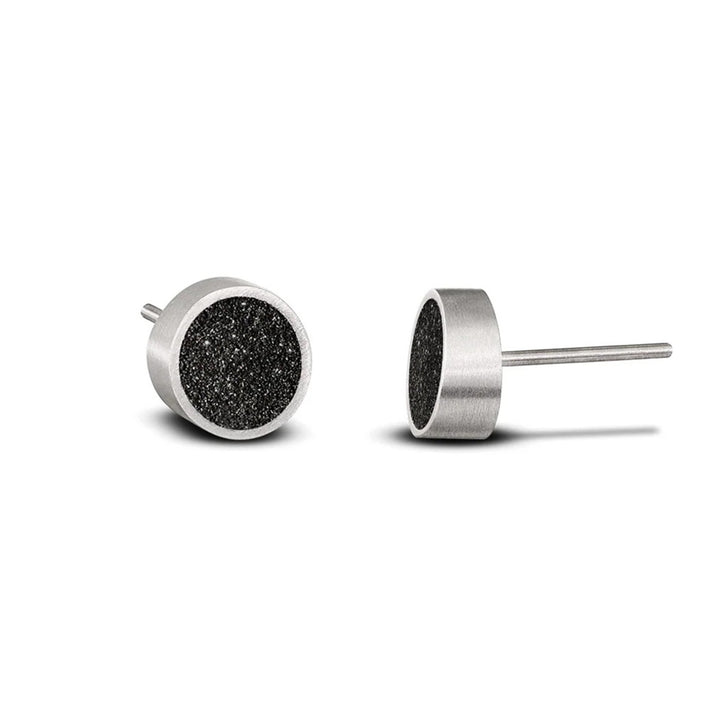 These delicate stainless steel stud earrings feature a dark, shiny centerpiece made of concrete and diamond dust. The border encasing it is stainless steel.