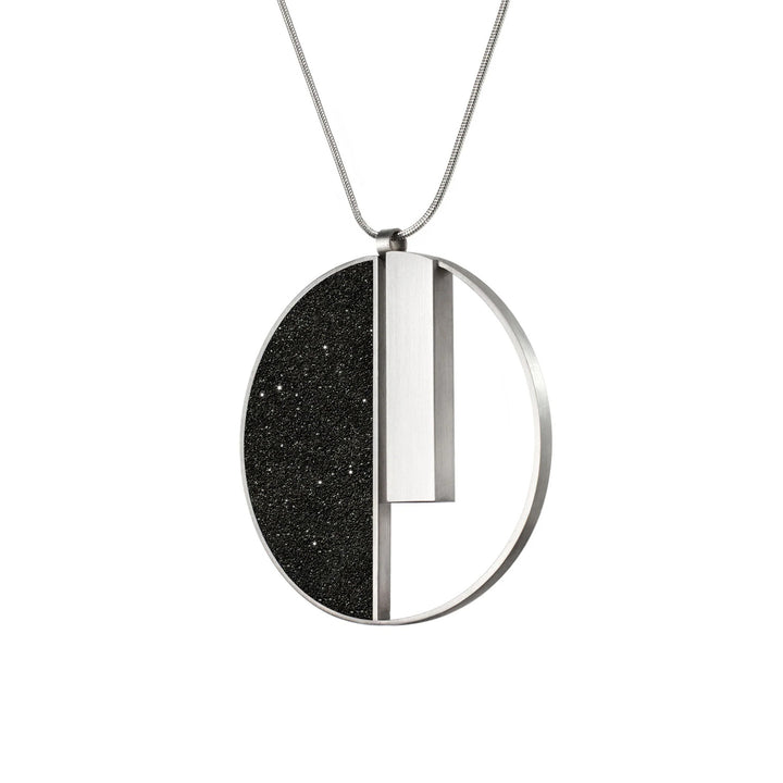 This stainless steel necklace is round in shape. The left side is black in colour with sparkles while the right side has been cut out except for a long, vertical bar hanging from the top.
