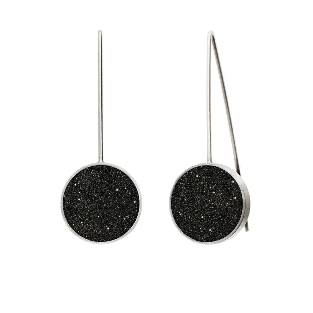 These stainless steel earrings feature a round centerpiece made of black-tinted concrete and diamond dust with a stainless steel border and hooks.