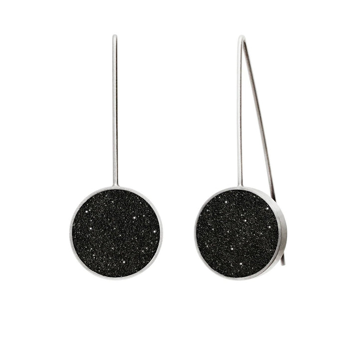 These stainless steel earrings feature a round centerpiece made of black-tinted concrete and diamond dust with a stainless steel border and hooks.