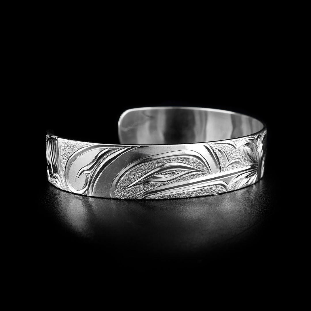 This Hummingbird and Eagle bracelet has a single, sterling silver band with a gap in the back. The head of the Hummingbird is on one side of the band and the Eagle's head on the other. The eyes, beaks and feather details are detailed, as well as a flower at the end of the Humming's beak.