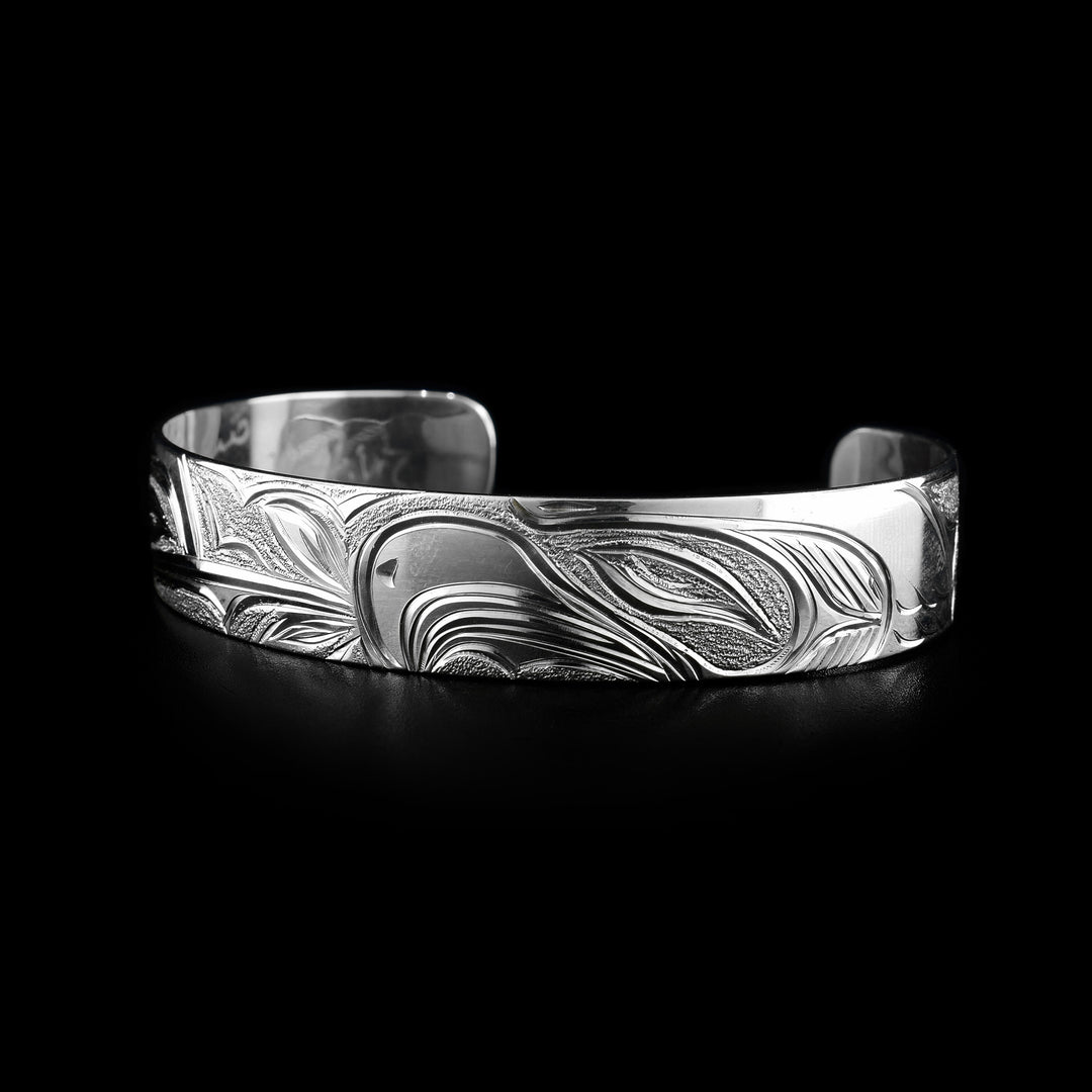This Hummingbird and Eagle bracelet has a single, sterling silver band with a gap in the back. The head of the Hummingbird is on one side of the band and the Eagle's head on the other. The eyes, beaks and feather details are detailed, as well as a flower at the end of the Humming's beak.