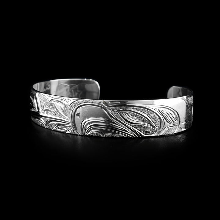 This Hummingbird and Eagle bracelet has a single, sterling silver band with a gap in the back. The head of the Hummingbird is on one side of the band and the Eagle's head on the other. The eyes, beaks and feather details are detailed, as well as a flower at the end of the Humming's beak.