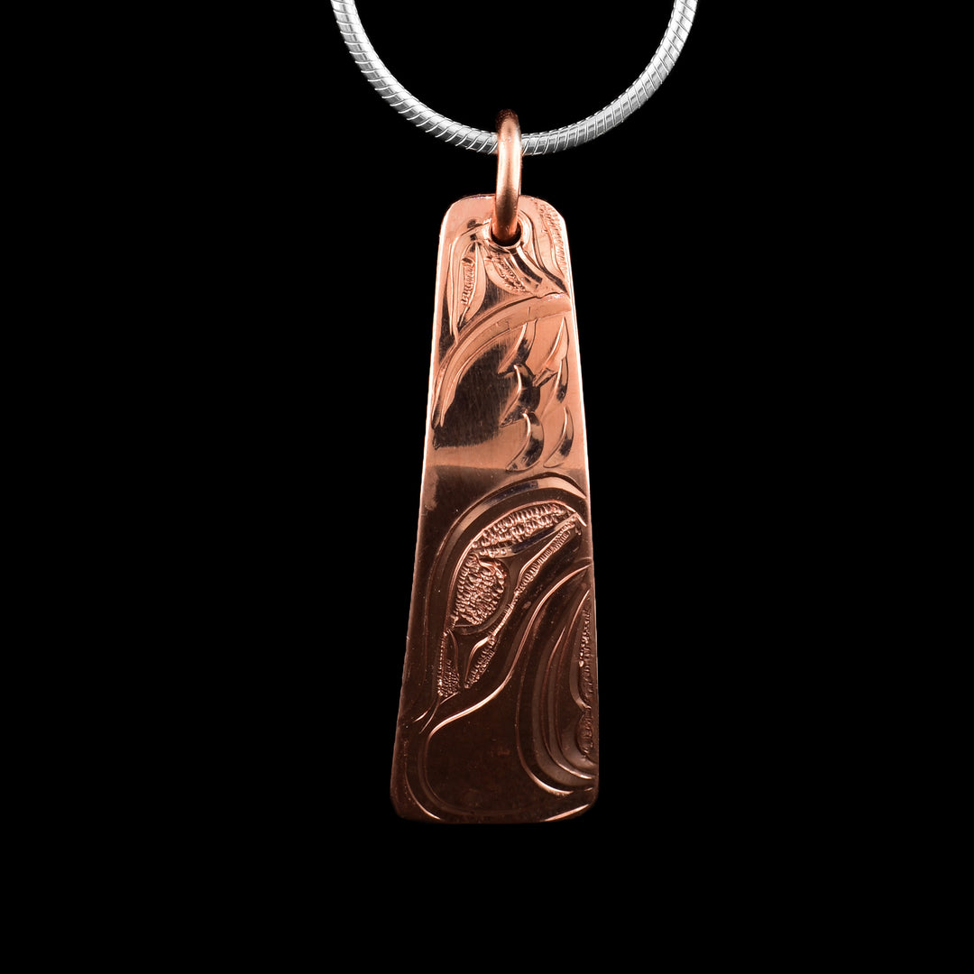 This Eagle pendant has a long, thin and oblong shape that tapers out at the bottom. The piece is made from copper and the head of the Eagle is carved into the it at a side profile. The eye, beak and feather designs are all detailed.