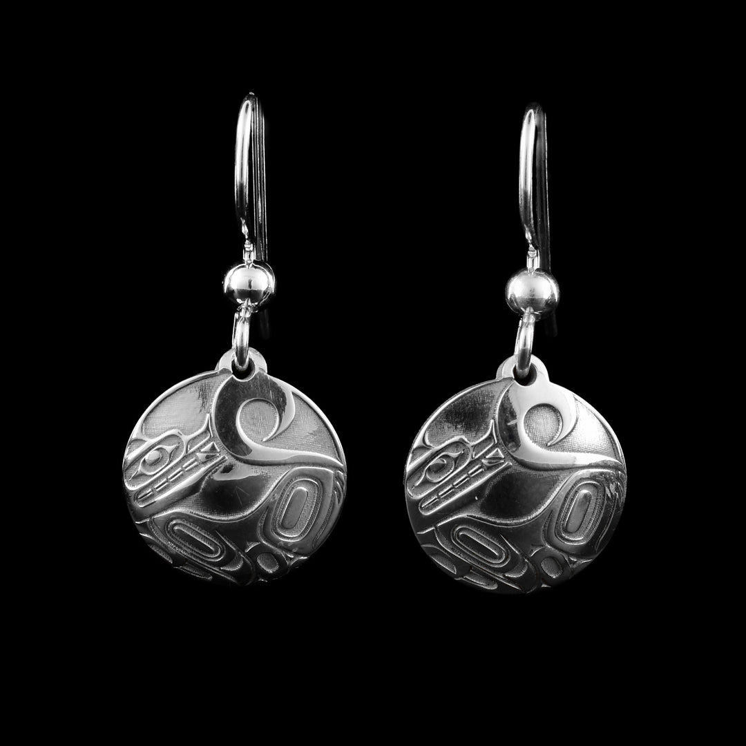 These Wolf dangle earrings have small, circle hangs made from sterling silver. A depiction of the Wolf legend is made on the hangs in a side profile. The Wolf is laying on the bottom of the hangs with its head looking up and its tail curls up to the top of the piece.