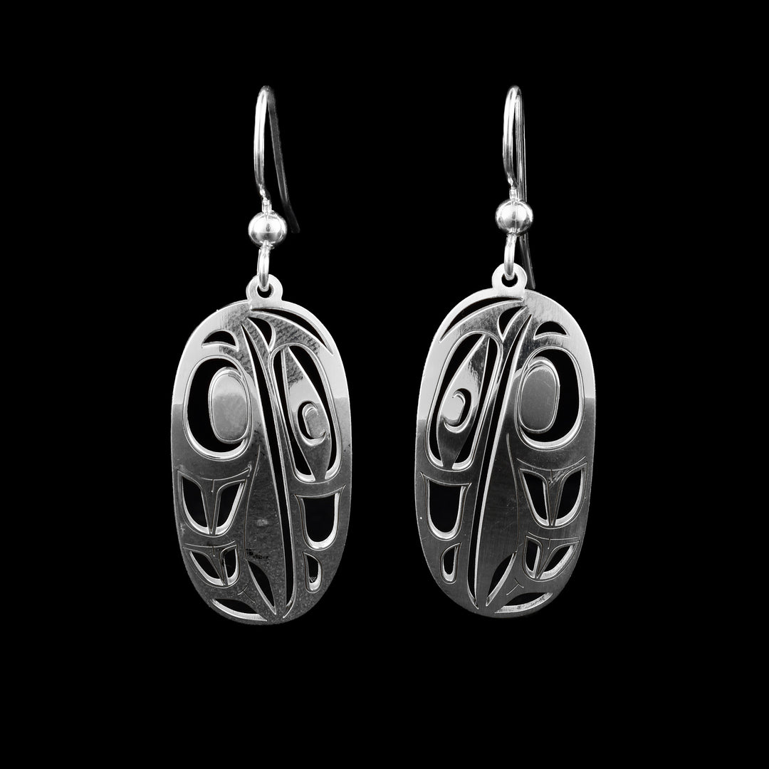 These oval raven earrings have long, oval shaped hangs made from sterling silver. There are cutouts made on the hangs with the raven's beak and eye on one half and its wing on the other side.