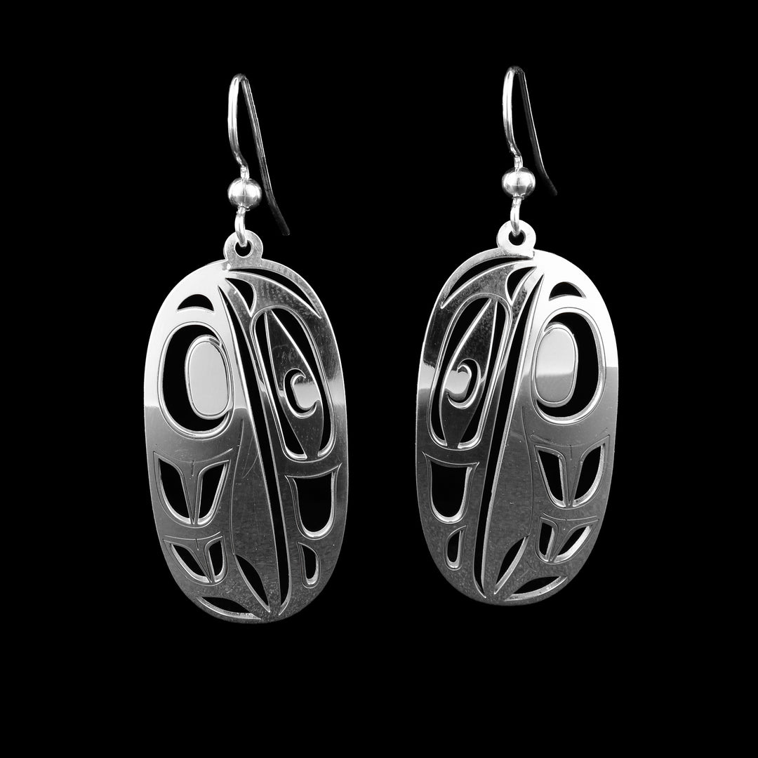 These oval raven earrings have long, oval shaped hangs made from sterling silver. There are cutouts made on the hangs with the raven's beak and eye on one half and its wing on the other side.