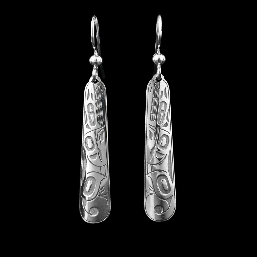 These long drop earrings silver have long, thin hangs with round edges. The hangs are made from sterling silver and are slightly wide at the bottom than the top. The Wolf legend is depicted in the surface of them with their body spanning across the hangs. The head is at the top with its eye, teeth, nose and ears shown. You can see its front and back paws and its tailed its curled up at the bottom.