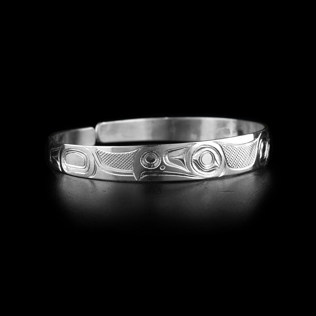 This Eagle cuff bracelet has a single, thin band with a gap in the back. The band is made from sterling silver and there are tow depictions of the Eagle carved into it. There are two eagle heads at the top of the band facing away from each other. There are wing details on the ends of the band.