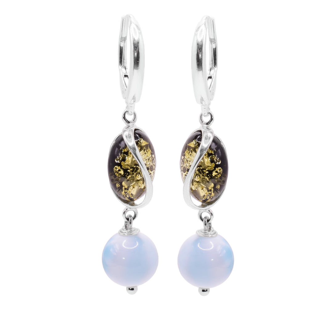 These amber dangle earrings have oval shaped amber beads with a curvy sterling silver designs encasing it. below them, there are sphere shaped larimar gemstone beads that are dangling.