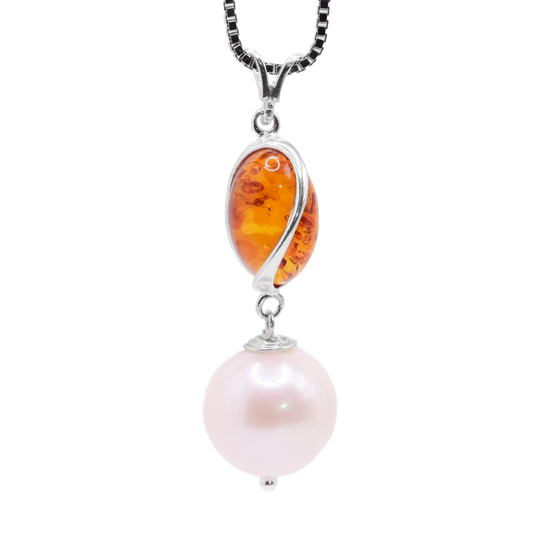 This freshwater pearl drop pendant has a sterling silver charm with deep, spiral ridges in it. In these ridges, there are amber pieces. Below the dangling charm, there is a large, sphere shaped pearl bead and the piece is held together using sterling silver.