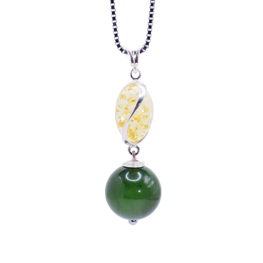 This jade pendant has a sterling silver charm with deep, spiral ridges in it. In these ridges, there are amber pieces. Below the dangling charm, there is a large, sphere shaped jade bead and the piece is held together using sterling silver.