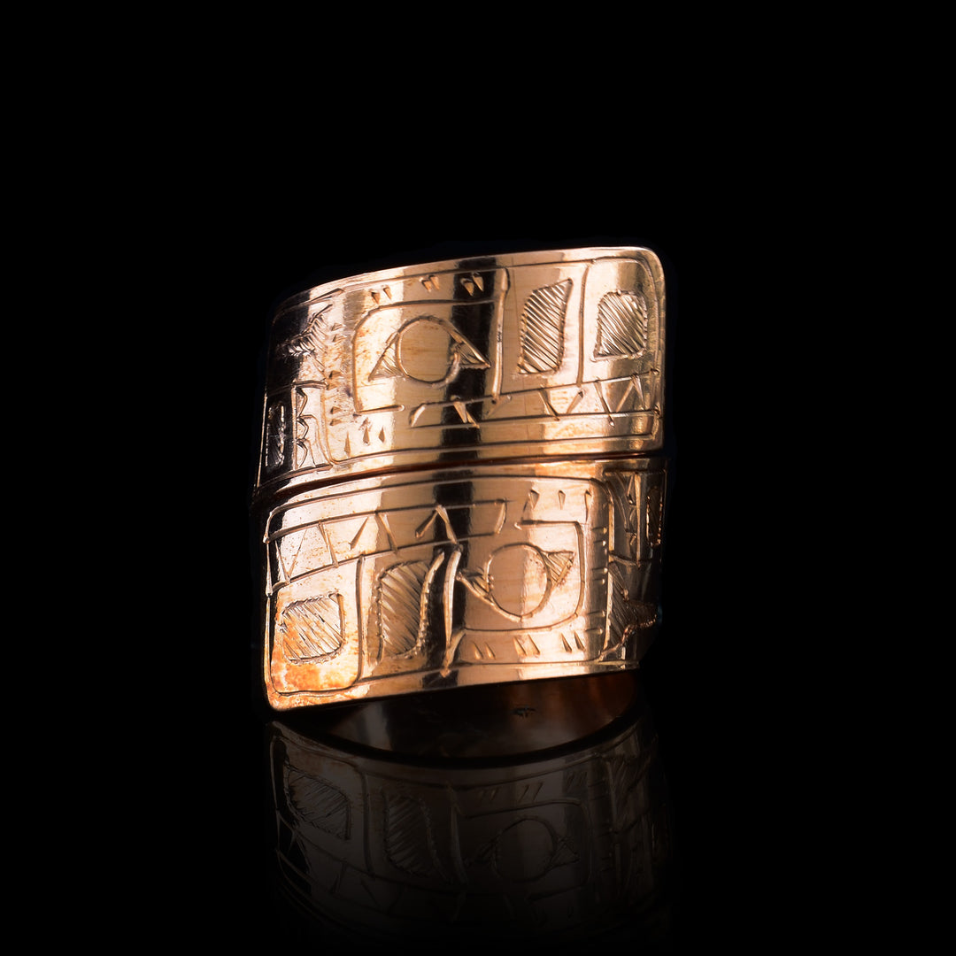 This copper wrap around ring has a single band that wraps around the finger twice. There is a depiction of the wolf head at one end of the band and another on the other end. The depictions are done in a side profile.