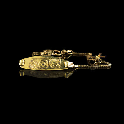 This dainty gold bracelet is made from 10K gold and has dainty chain made from small, square links. There is a flat piece in the middle of the chain with a depiction of the Bear carved into it. The head of the Bear is shown at a side profile on the bar.