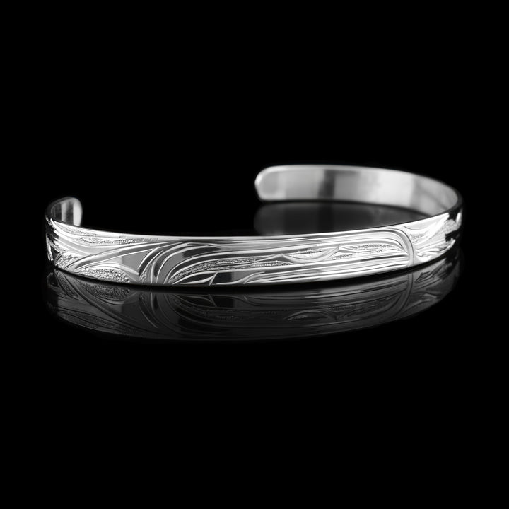 This Hummingbird and Orca bracelet has a single, sterling silver band with a gap in the back. The head of the Hummingbird is on one side of the band and the Orca's head on the other. The legends are facing each other and there is a wing design behind the hummingbird.