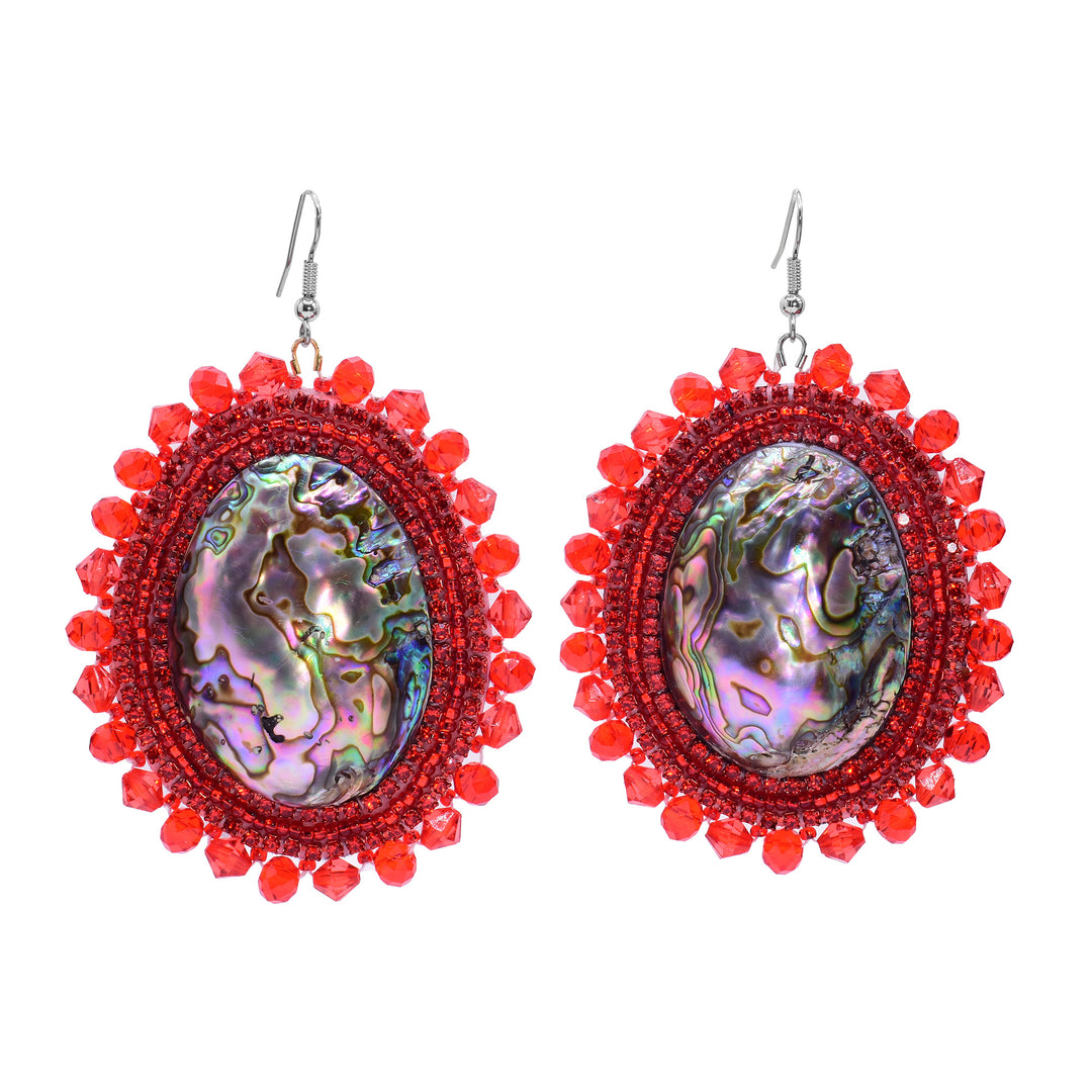 These dangling beaded earrings have large, oval shaped abalone hangs with chromatic colours on the surface of them. There are red beads woven into a pattern around the outside of the piece. There are small beads lining the circumference of the abalone and larger beads on the very outside of the hangs.