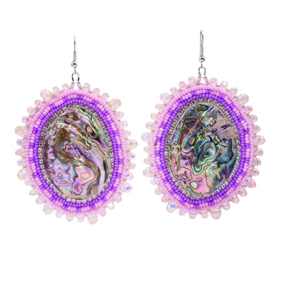These dangling beaded earrings have large, oval shaped abalone hangs with chromatic colours on the surface of them. There are different coloured pink beads and purple highlight beads woven into a pattern around the outside of the piece. There are small beads lining the circumference of the abalone and larger beads on the very outside of the hangs.
