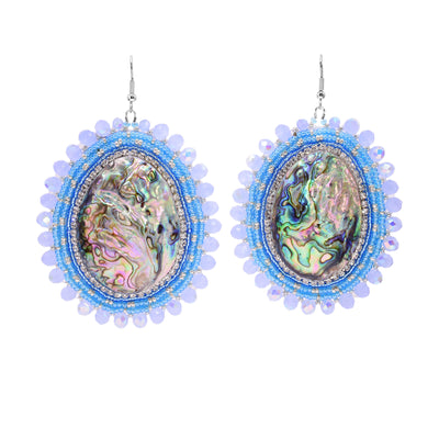 These dangling beaded earrings have large, oval shaped abalone hangs with chromatic colours on the surface of them. There are different coloured sky blue beads and gold highlight beads woven into a pattern around the outside of the piece. There are small beads lining the circumference of the abalone and larger beads on the very outside of the hangs.