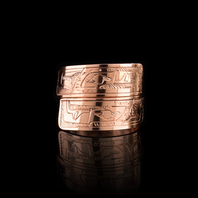 This copper wrap around ring has a single band that wraps around the finger twice. There is a depiction of the Eagle head at one end of the band and another on the other end. The depictions are done in a side profile with hatching design in the background of the scene.