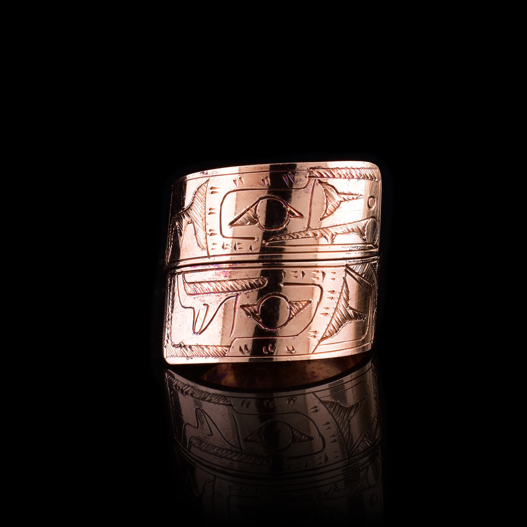 This copper wrap around ring has a single band that wraps around the finger twice. There is a depiction of the Eagle head at one end of the band and the Raven on the other end. The depictions are done in a side profile.