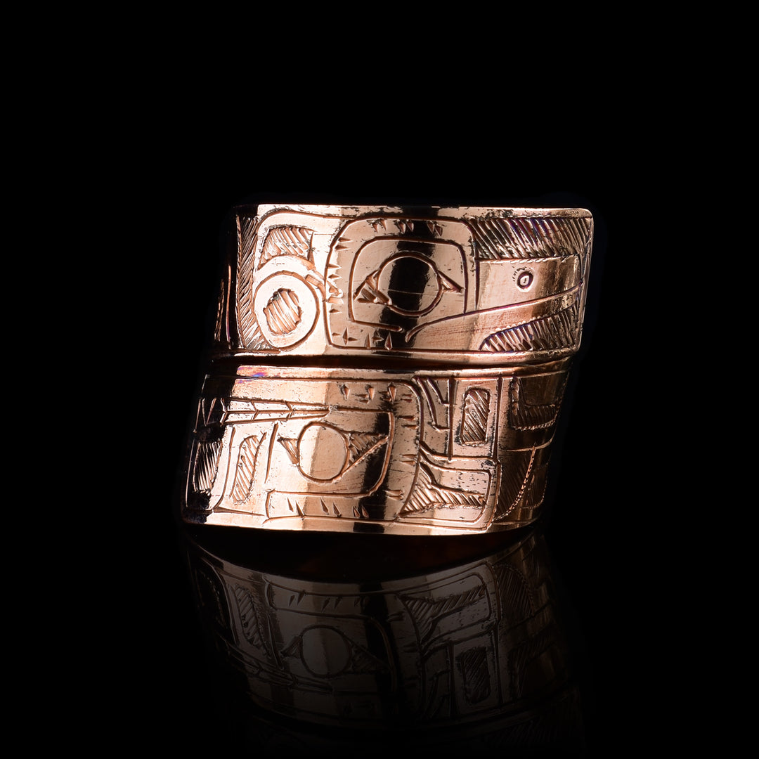 This copper wrap around ring has a single band that wraps around the finger twice. There is a depiction of the wolf head at one end of the band and the Hummingbird on the other end. The depictions are done in a side profile.