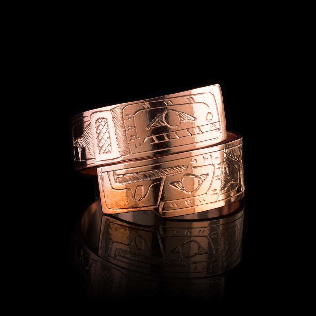 This copper wrap around ring has a single band that wraps around the finger twice. There is a depiction of the Eagle head at one end of the band and the Orca on the other end. The depictions are done in a side profile.