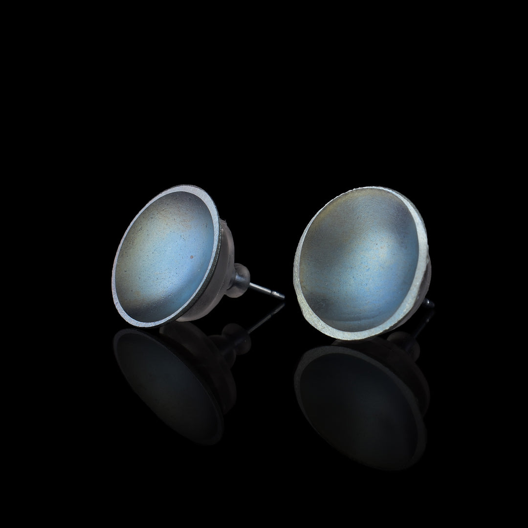 These titanium earrings studs are circle shaped and have a deep concave. The studs have a shiny, light blue grey colour on their surface
