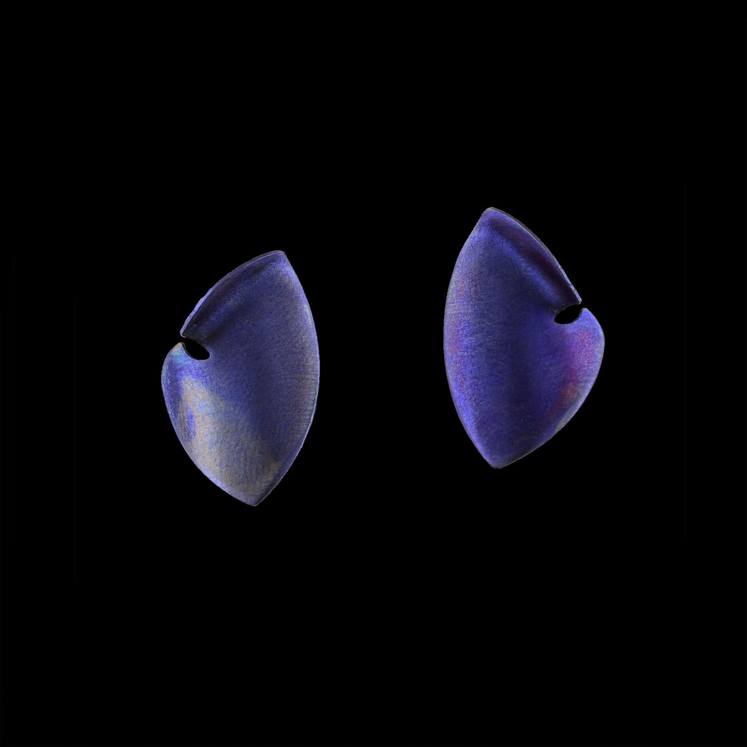 These titanium earrings studs are made from purple titanium and there are large and teardrop shaped. The studs curve to a point at both ends and there is a small cutout on the side of the studs.