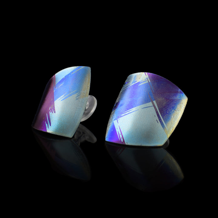 These colourful titanium earrings are convex and have an uneven, square shape. There are splashes of pink, purple and blue with paint brush designs made across the surface of the studs.