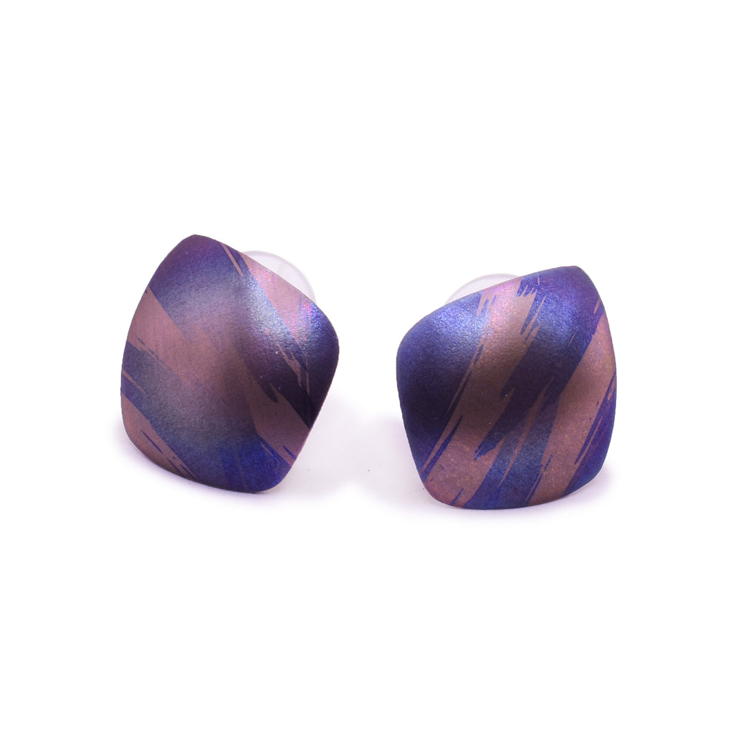 These small colourful titanium earrings are convex and have an uneven, square shape. There are splashes of pink, purple and blue with paint brush designs made across the surface of the studs.