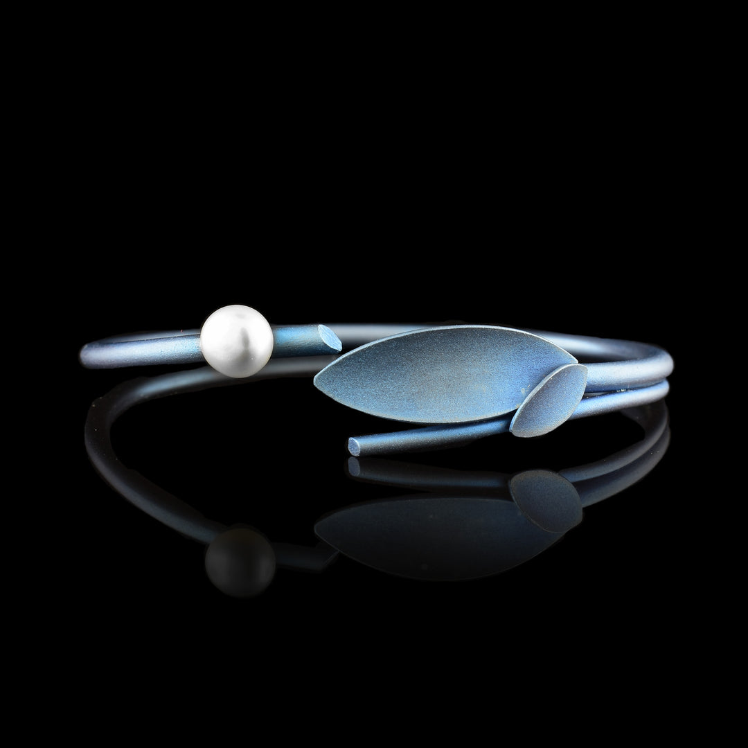 This beautiful titanium bracelet bangle is made from light blue titanium wire that does not connect at the end. There are two leaf designs at one end of the bracelet and a pearl behind the leaf details.