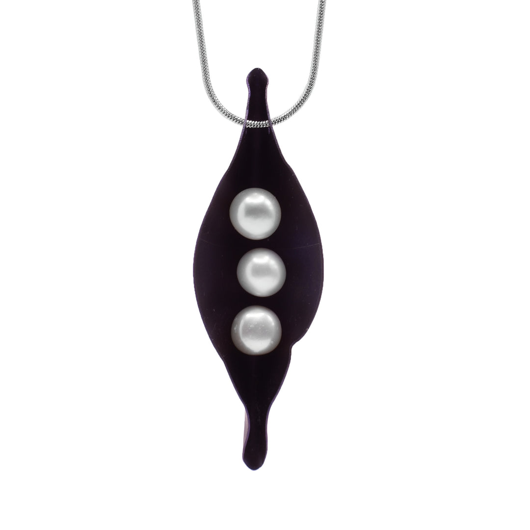 This pearl drop pendant necklace is made from a long, oval shaped piece of purple titanium. The titanium represents a pea pod and is curved up with three white pearls that represent the peas.