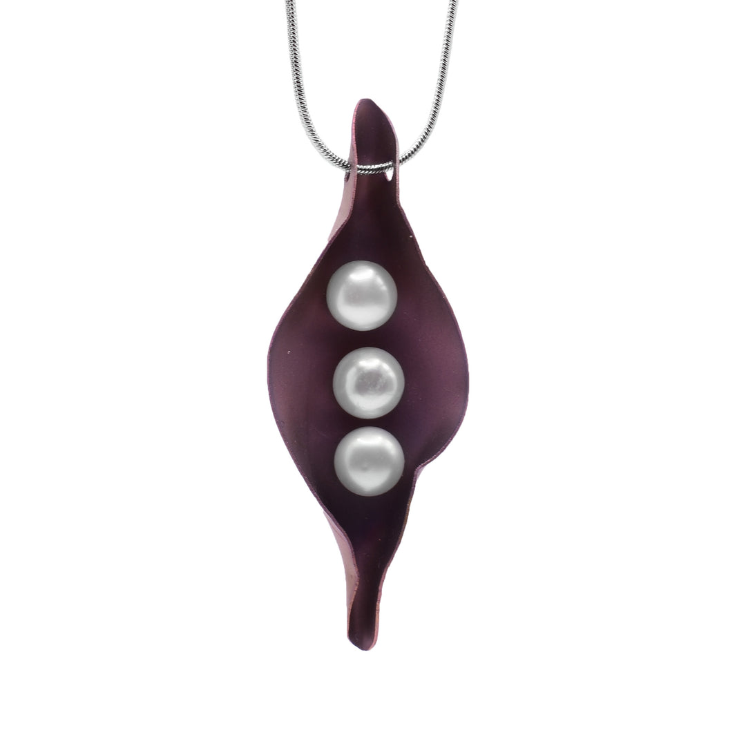 This pearl drop pendant necklace is made from a long, oval shaped piece of rose gold colored titanium. The titanium represents a pea pod and is curved up with three white pearls that represent the peas.