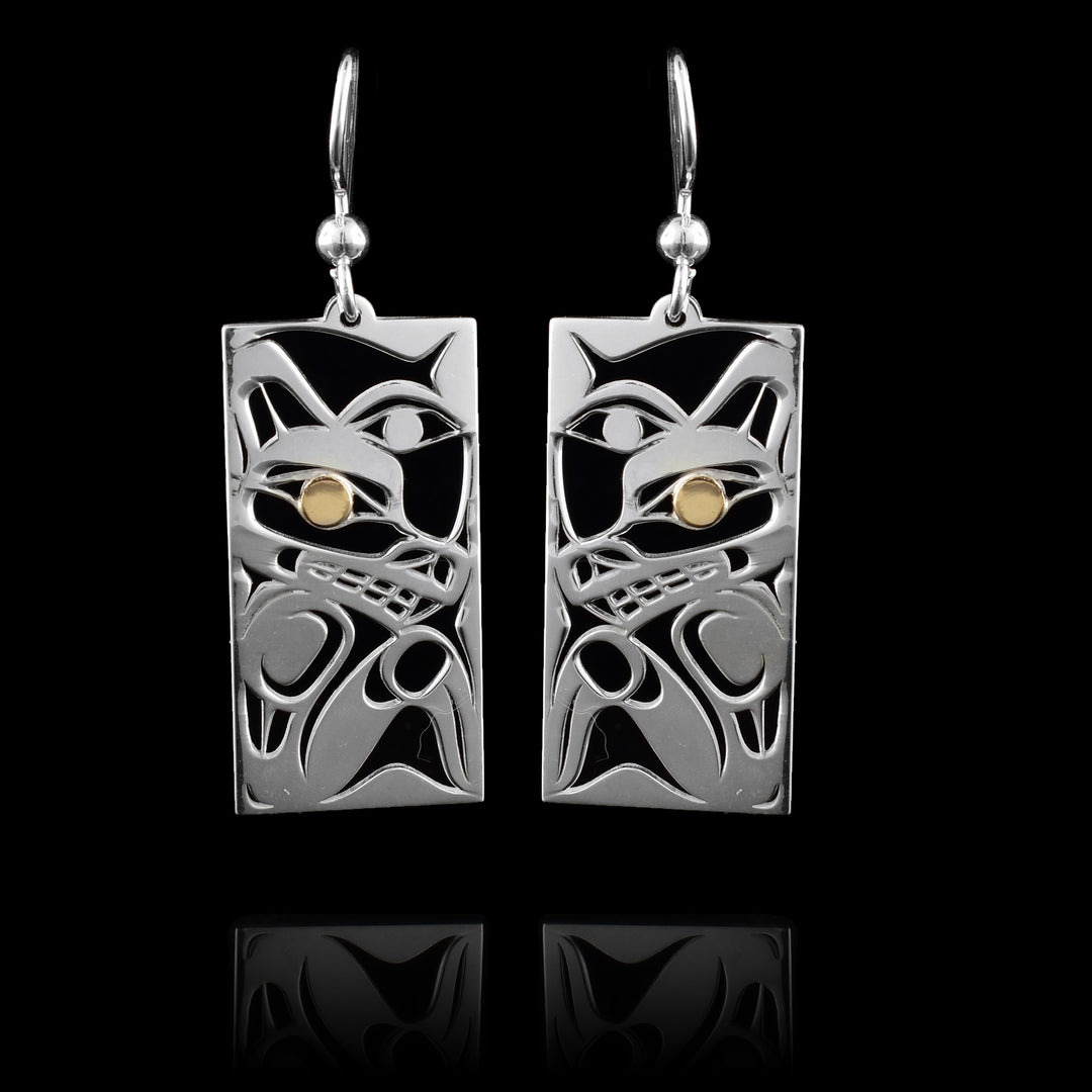 These Wolf Moon earrings have rectangle shaped hangs made from sterling silver and with cutout designs depicting the Wolf and the Moon legends. There are cutouts designing the head of the Wolf in a side profile and its eye is done in 14K gold. Beside the Wolf, half of the Moon is shown with its eye visible.