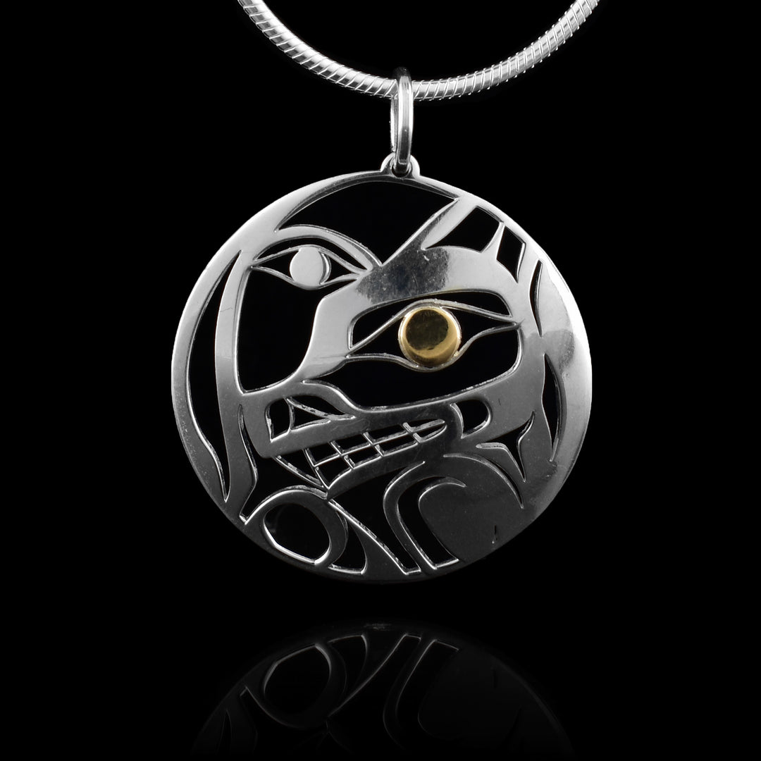 This Wolf and Moon Pendant has a circle shape and is made from sterling silver. There are cutouts designing the head of the Wolf in a side profile and its eye is done in 14K gold. Beside the Wolf, half of the Moon is shown with its eye visible.